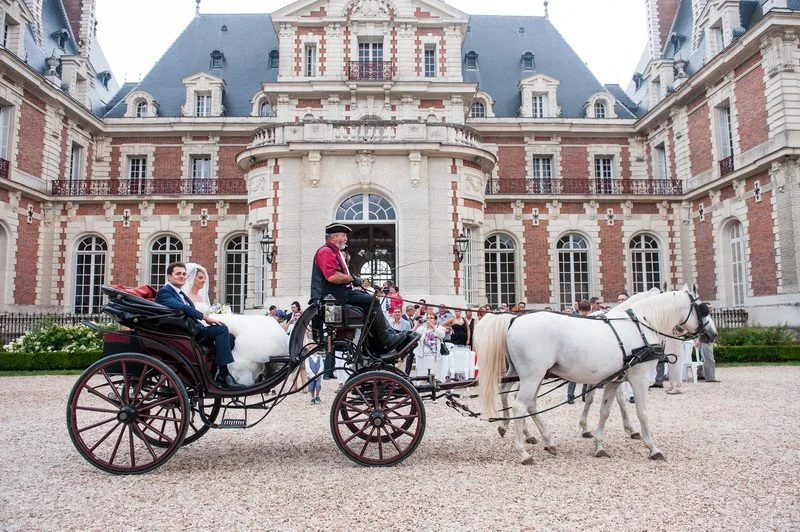 Les mariés en calèche dans la cour d'honneur d'un château