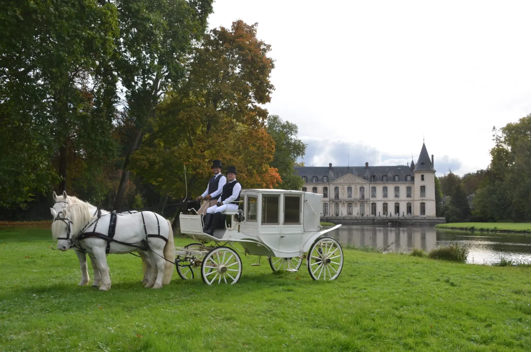 Calèche blanche et cheval de trait devant un château et son étang en automne — mariage en calèche