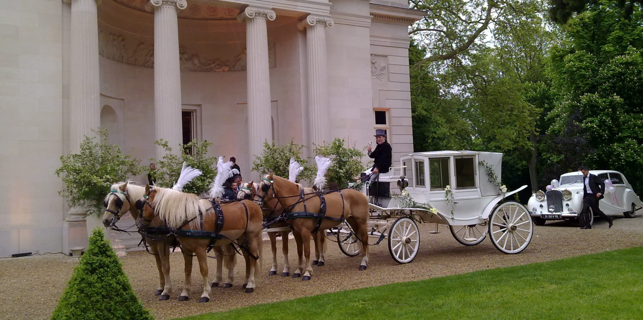Landau de mariage et chevaux à plumets devant un château