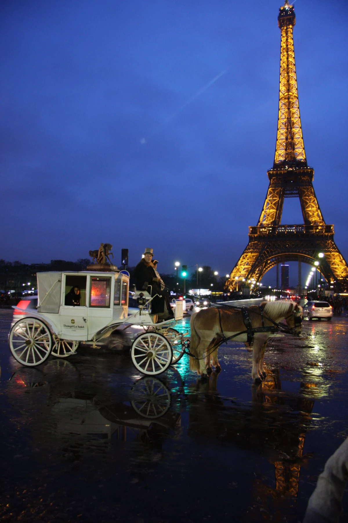 Calèche blanche de l'hôtel Shangri-La devant la tour Eiffel illuminée, la nuit