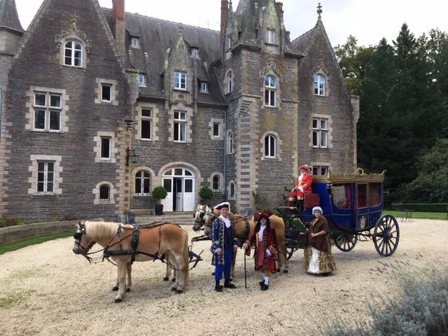 Carrosse royal bleu, cochers et personnages en costumes d'époque devant un château