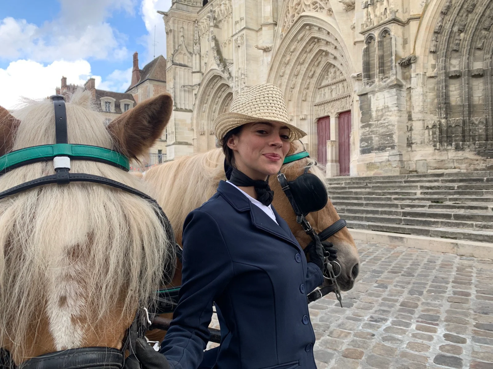 Meneuse en redingote et chapeau de paille tenant ses haflingers devant le parvis de l'église